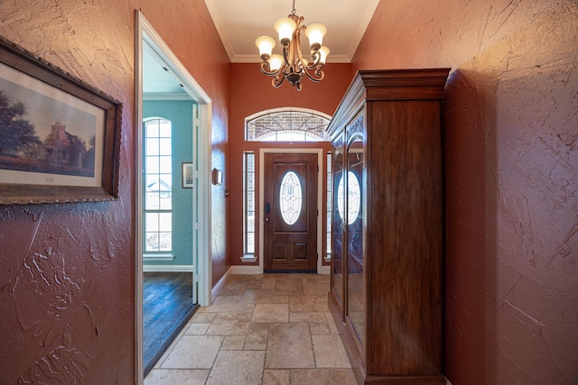 166 Cactus Dr, Decatur, TX 76234 - foyer featuring a textured wall, a notable chandelier, baseboards, ornamental molding, and stone tile flooring