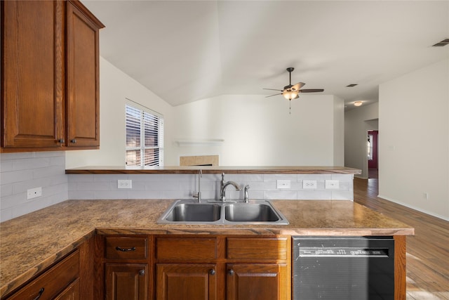 kitchen featuring sink, vaulted ceiling, dishwasher, light hardwood / wood-style floors, and decorative backsplash