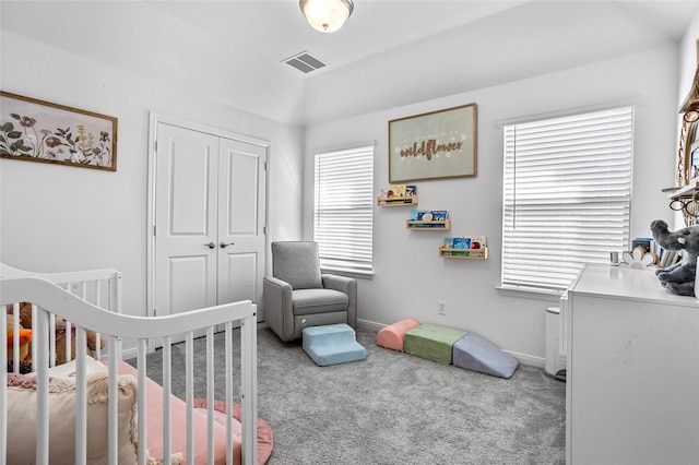 bedroom with a nursery area, carpet flooring, and a closet