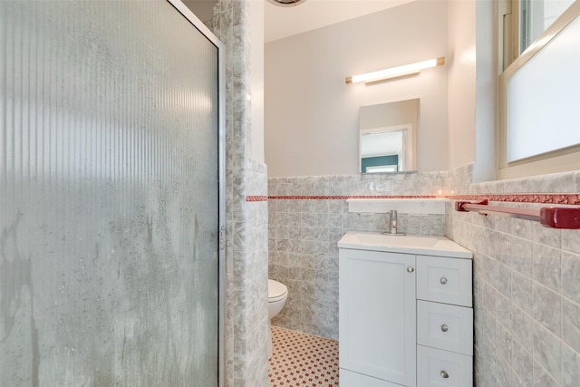 bathroom with toilet, an enclosed shower, tile walls, vanity, and tile patterned flooring