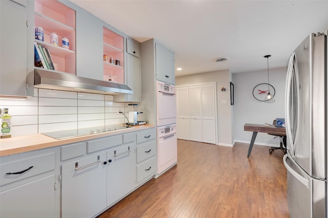 kitchen with stainless steel fridge, electric stovetop, pendant lighting, oven, and backsplash