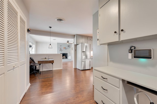 kitchen with white cabinetry, decorative light fixtures, dark wood-type flooring, and stainless steel refrigerator with ice dispenser