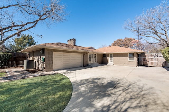 ranch-style home with a garage, central AC, and a front yard