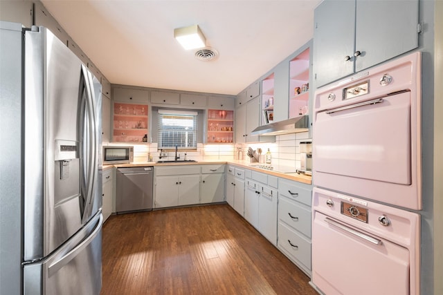 kitchen featuring appliances with stainless steel finishes, sink, backsplash, and dark hardwood / wood-style floors