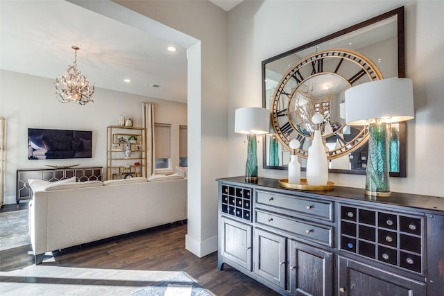 bar featuring dark hardwood / wood-style flooring and a notable chandelier