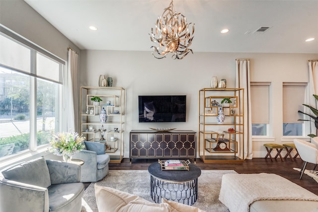 living room featuring a notable chandelier, dark wood-type flooring, and a healthy amount of sunlight