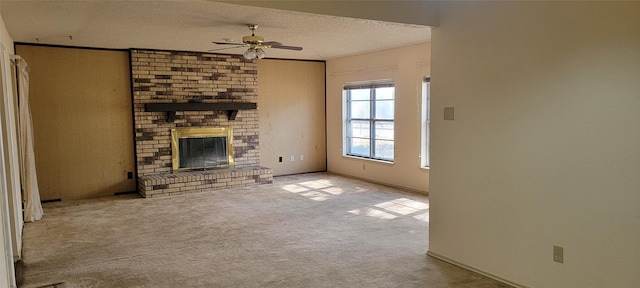 unfurnished living room with crown molding, light colored carpet, a brick fireplace, a textured ceiling, and ceiling fan