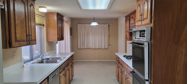 kitchen with hanging light fixtures, sink, a textured ceiling, and stainless steel appliances