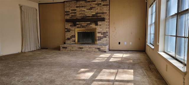 unfurnished living room featuring light colored carpet and a brick fireplace