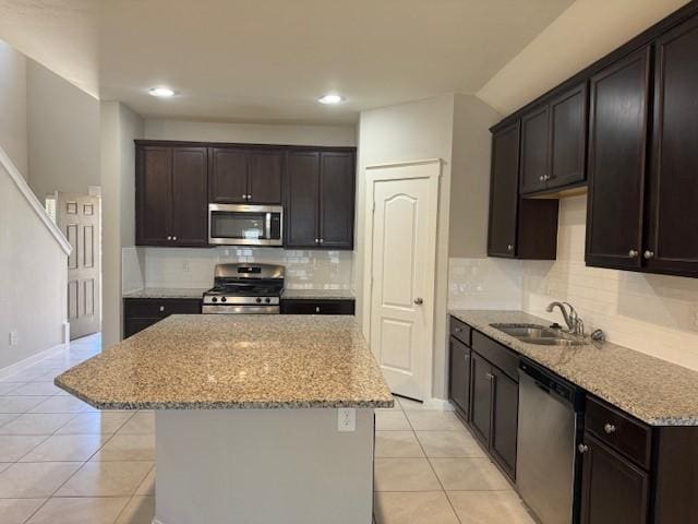 kitchen featuring sink, light tile patterned floors, a kitchen island, and appliances with stainless steel finishes