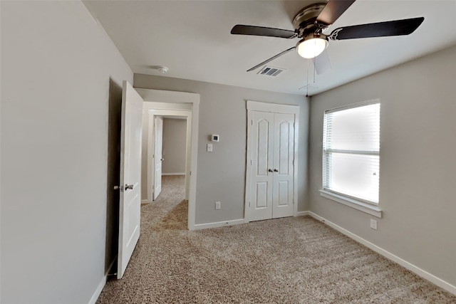 unfurnished bedroom featuring ceiling fan, a closet, and light carpet