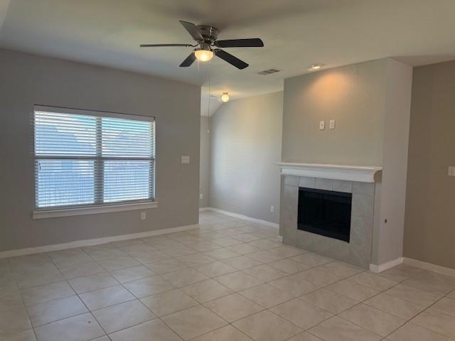 unfurnished living room with ceiling fan, a fireplace, and light tile patterned floors