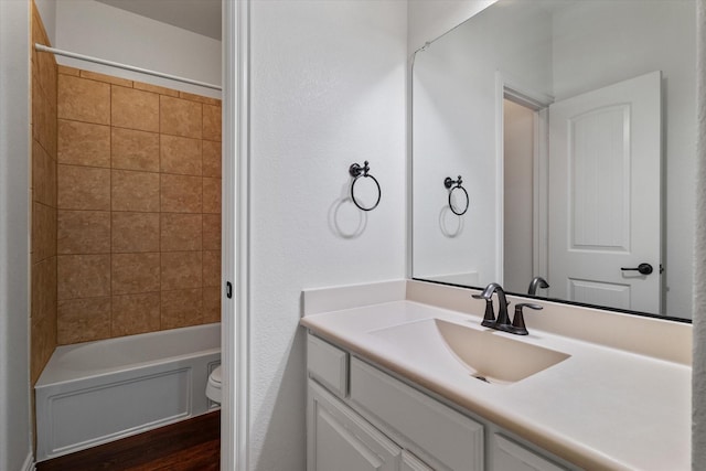 full bathroom featuring vanity, tiled shower / bath, and toilet