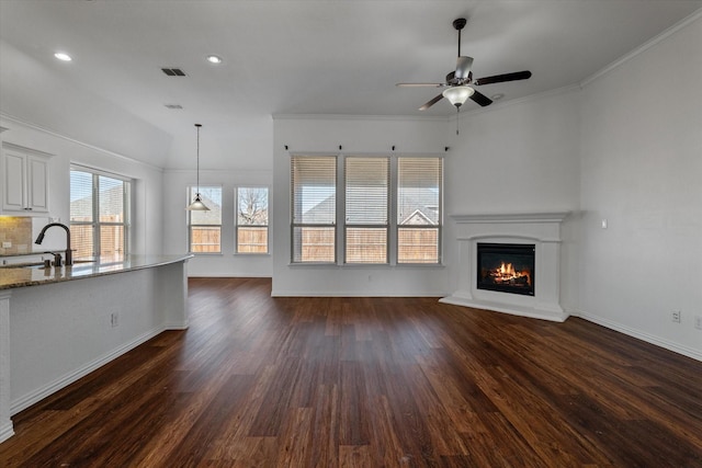 unfurnished living room featuring dark wood-type flooring, ceiling fan, ornamental molding, and sink