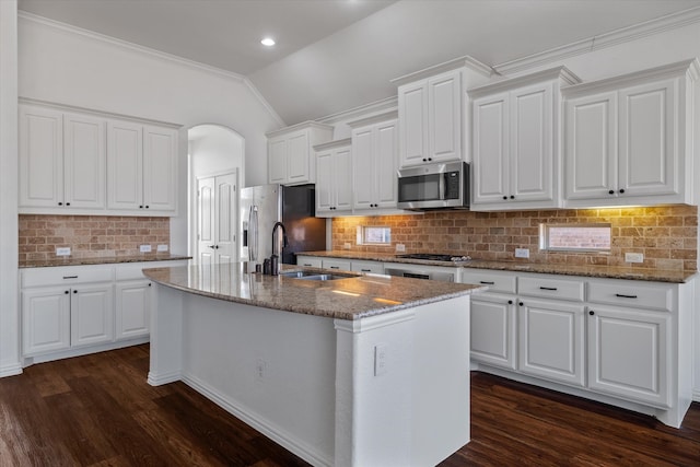 kitchen with sink, stainless steel appliances, an island with sink, white cabinets, and stone countertops