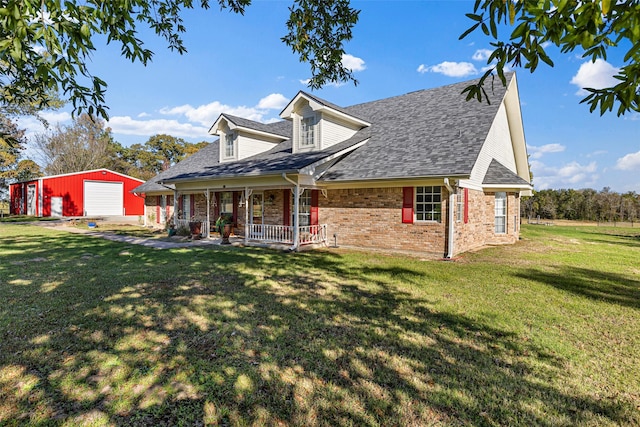 cape cod home with an outbuilding, a garage, a front lawn, and covered porch