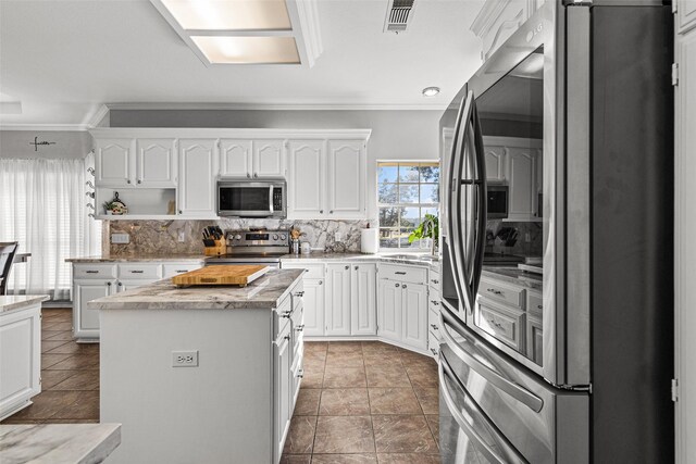 kitchen featuring stainless steel appliances, a center island, white cabinets, and dark tile patterned floors