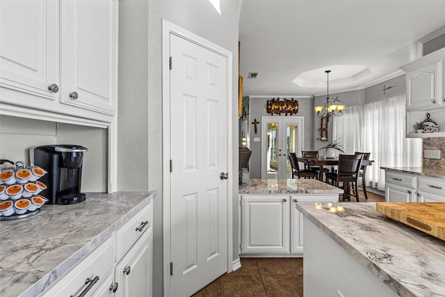 kitchen with white cabinetry, hanging light fixtures, dark tile patterned floors, a notable chandelier, and french doors