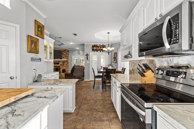 kitchen with french doors, decorative light fixtures, ornamental molding, stainless steel appliances, and white cabinets