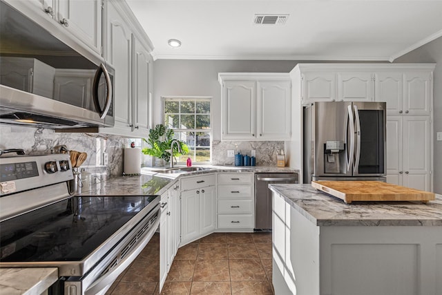 kitchen with white cabinetry, decorative backsplash, stainless steel appliances, and crown molding