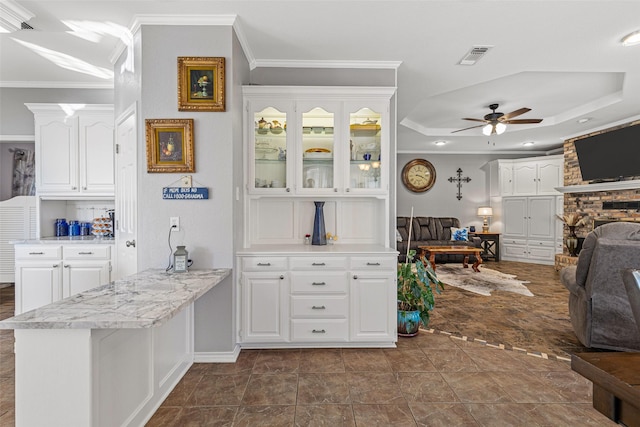 kitchen with white cabinetry, crown molding, kitchen peninsula, and ceiling fan