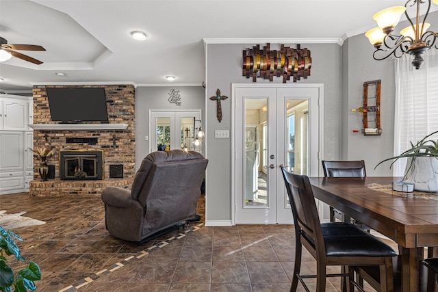 dining space with french doors, ornamental molding, a tray ceiling, and a brick fireplace