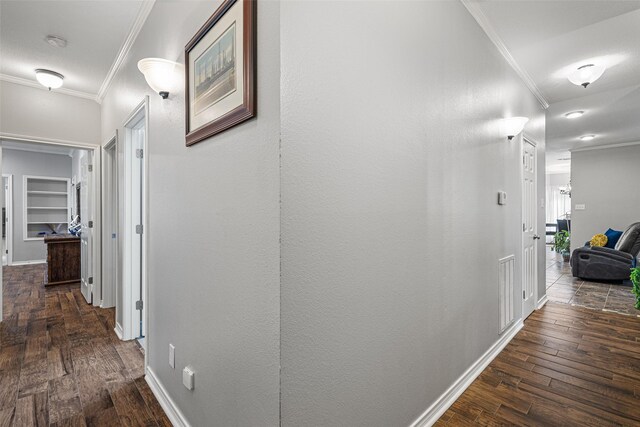 corridor with built in shelves, ornamental molding, and dark hardwood / wood-style floors