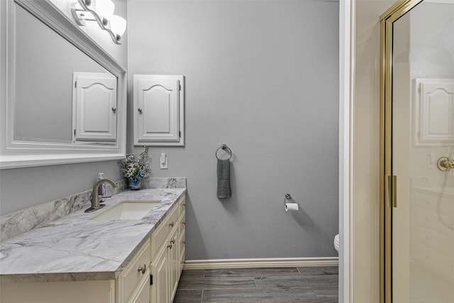 bathroom featuring vanity, wood-type flooring, a shower with door, and toilet