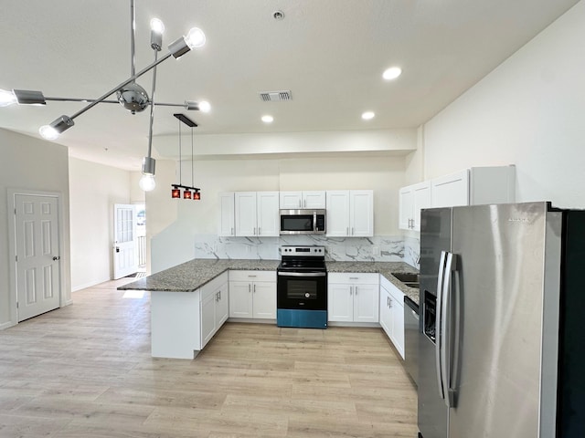 kitchen featuring dark stone counters, kitchen peninsula, white cabinets, stainless steel appliances, and backsplash