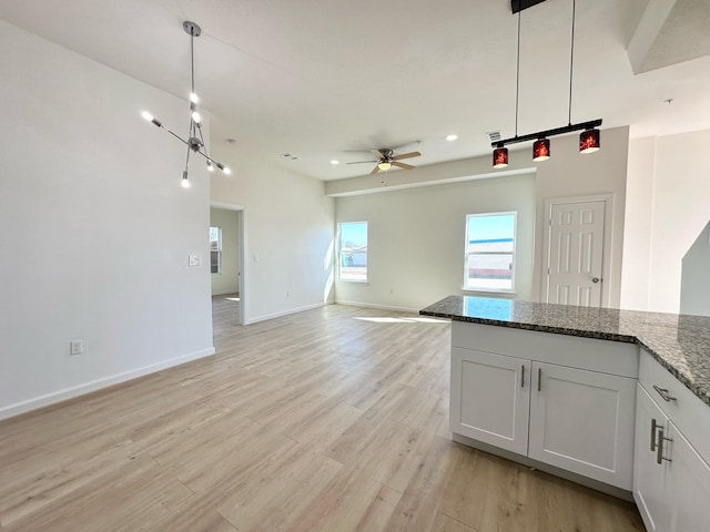 kitchen with pendant lighting, white cabinetry, light hardwood / wood-style flooring, and dark stone counters