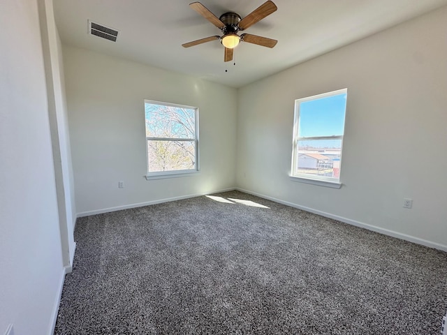 empty room with ceiling fan and dark carpet