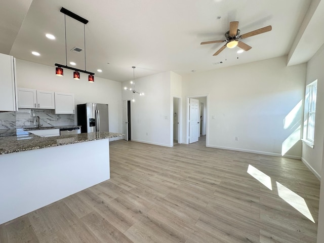 kitchen featuring white cabinetry, backsplash, dark stone counters, hanging light fixtures, and stainless steel appliances