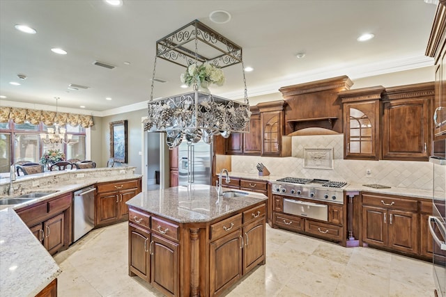 kitchen featuring hanging light fixtures, appliances with stainless steel finishes, a kitchen island with sink, and sink