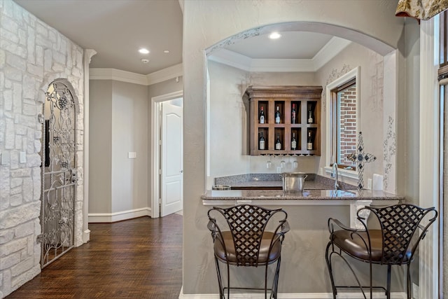 bar featuring dark hardwood / wood-style flooring, sink, ornamental molding, and stone counters