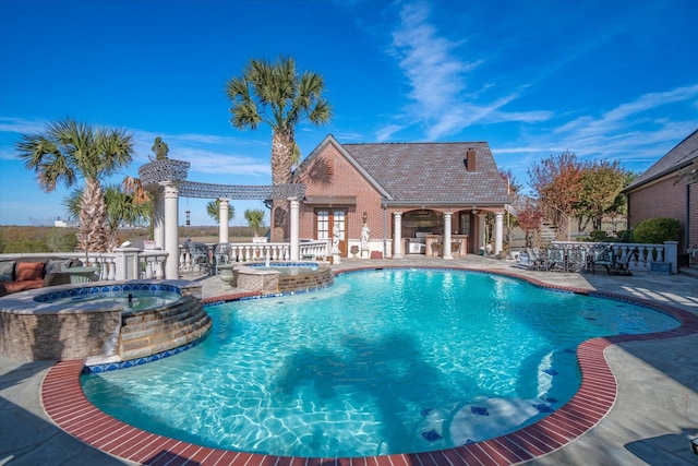 view of pool featuring an outbuilding, a patio area, pool water feature, and an in ground hot tub