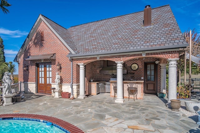 rear view of house with exterior kitchen, a patio area, french doors, and a bar