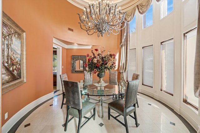 tiled dining space featuring an inviting chandelier, crown molding, and a high ceiling