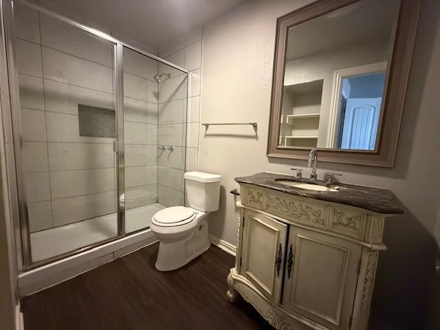 bathroom featuring vanity, hardwood / wood-style flooring, toilet, and walk in shower