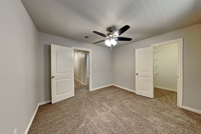 unfurnished bedroom featuring ceiling fan, a spacious closet, carpet floors, and a closet