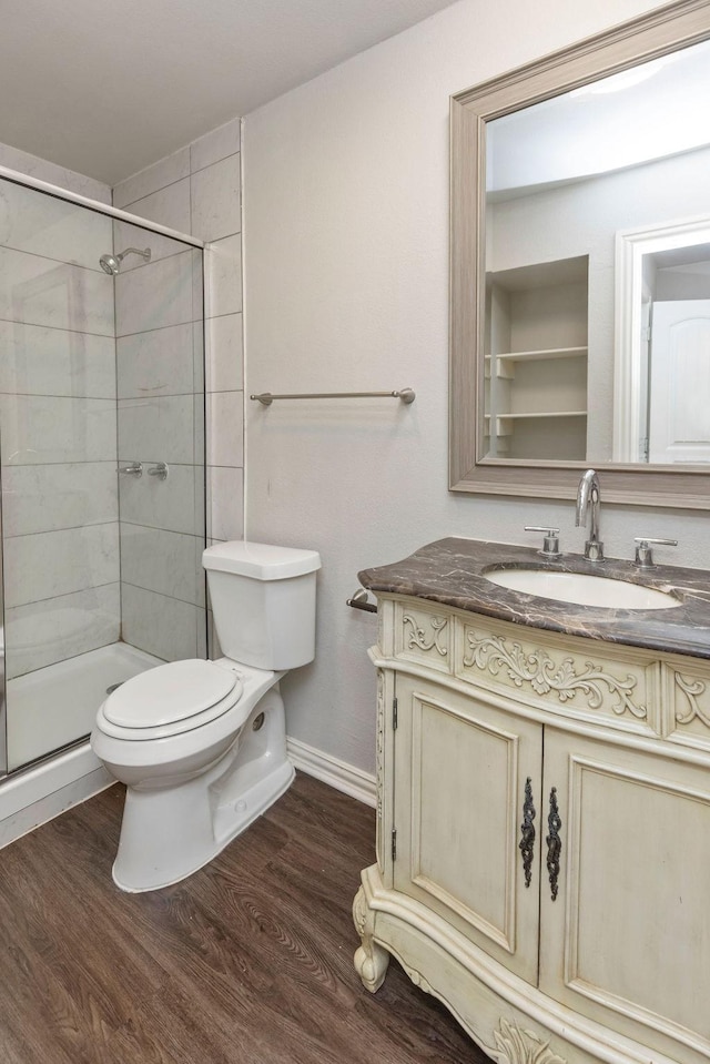 full bath with wood finished floors, toilet, vanity, and a tile shower