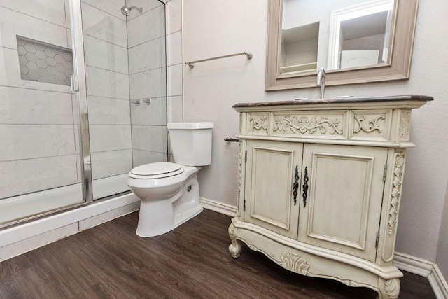 bathroom featuring a stall shower, toilet, wood finished floors, and baseboards