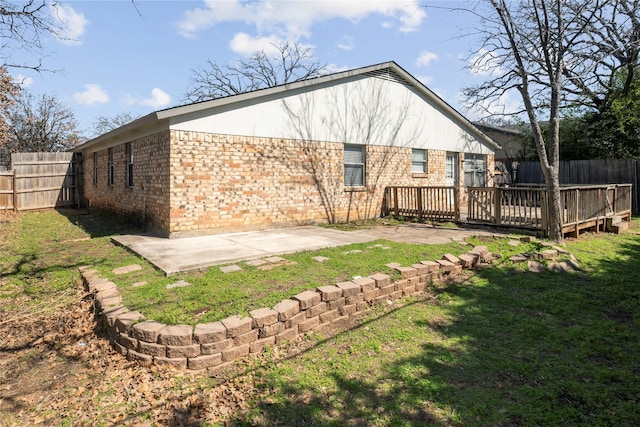rear view of house with brick siding, a deck, and a patio