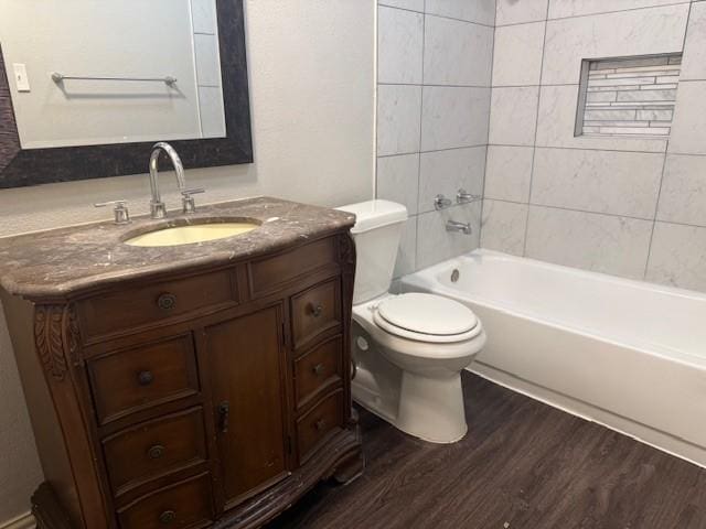 full bathroom with tiled shower / bath combo, wood-type flooring, vanity, and toilet