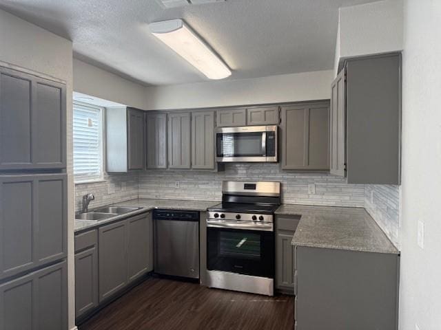 kitchen with gray cabinets, appliances with stainless steel finishes, sink, and dark wood-type flooring