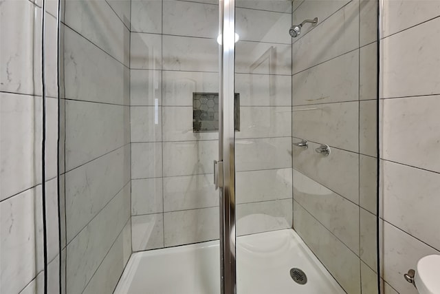 bathroom featuring a shower with door and toilet