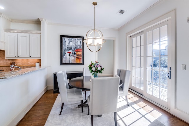 dining space with crown molding, plenty of natural light, dark wood-type flooring, and a chandelier