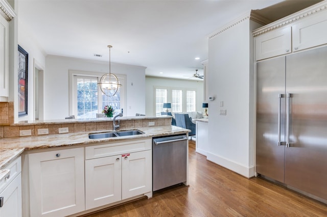 kitchen featuring sink, white cabinetry, hanging light fixtures, plenty of natural light, and stainless steel appliances