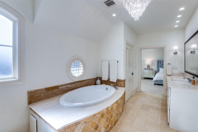 bathroom with a relaxing tiled tub, a healthy amount of sunlight, a chandelier, and vanity