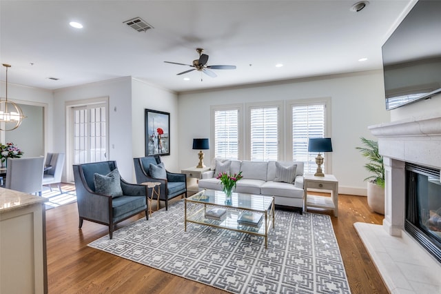 living room featuring ornamental molding, a tiled fireplace, and light hardwood / wood-style flooring