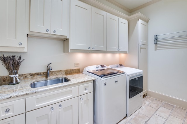 clothes washing area with sink, ornamental molding, washing machine and dryer, and cabinets